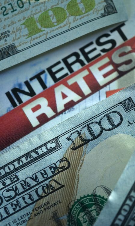 Imagen de billetes de 100 dólares con texto de "Interest Rates" se muestra en la sección Vender anualidad - conozca la tasa de descuento.