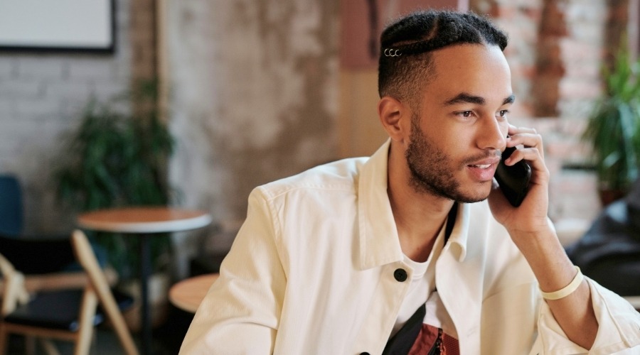 Guy on cell phone in cafe setting, looking to sell structured settlement and asking for a quote.